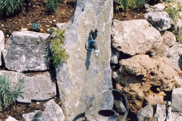 Brunnen und Wasserstelle für Gießkanne im Garten mit Steinoptik